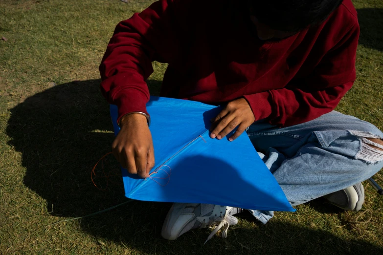 a man kneeling down with his hand in the kite