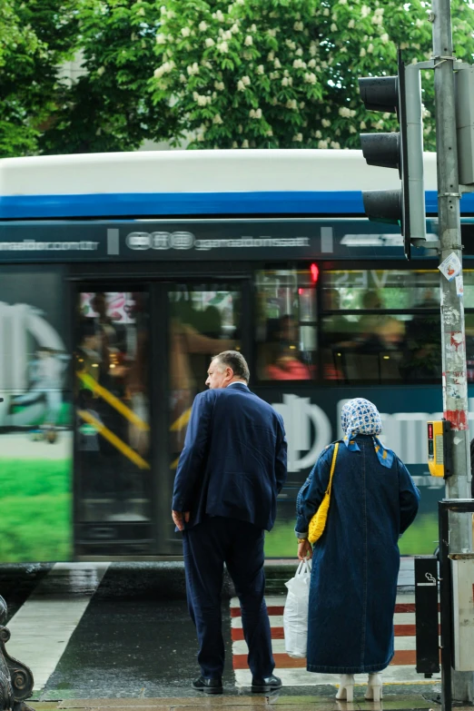 a couple of people waiting at a light on the side of a bus