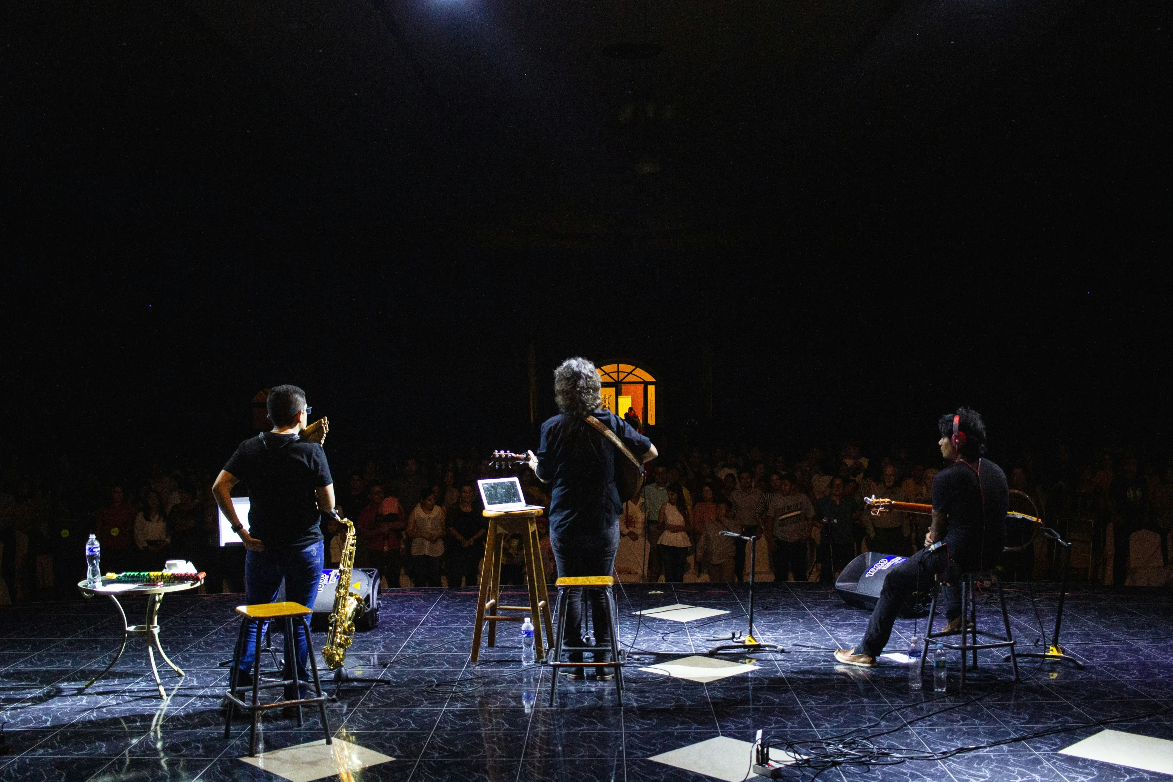 four musicians standing on stage with one person holding a microphone