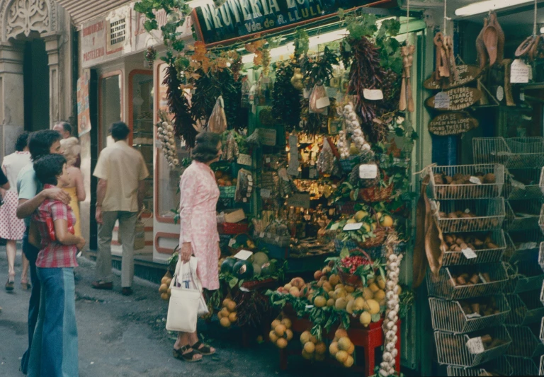 people walking by a market with lots of fresh produce