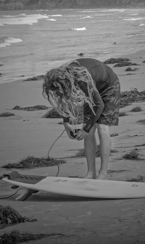 the  is looking at his surfboard at the shore