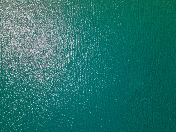 a green ocean and boat seen from above