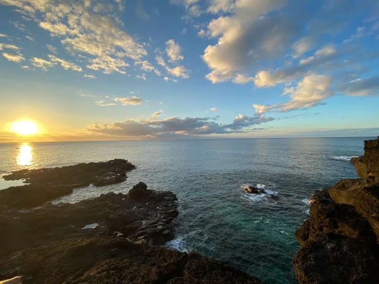 sunset over the ocean with small boats near by