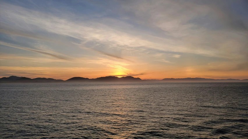 the sun sets over an island in the ocean