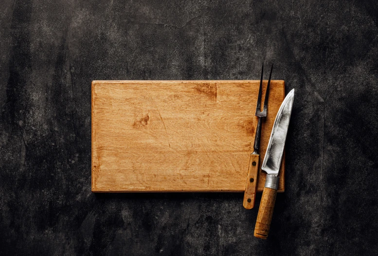 a knife and  board sitting on a black surface