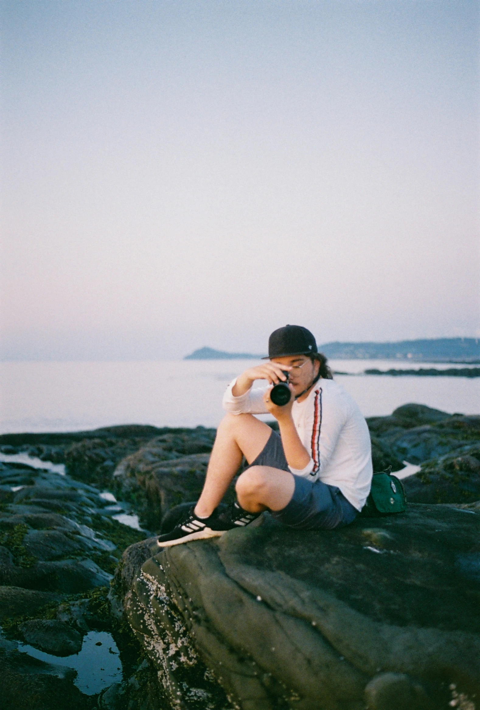 a man sitting on the rocks using his cell phone