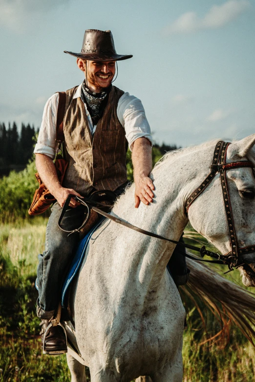 man riding a white horse through a field