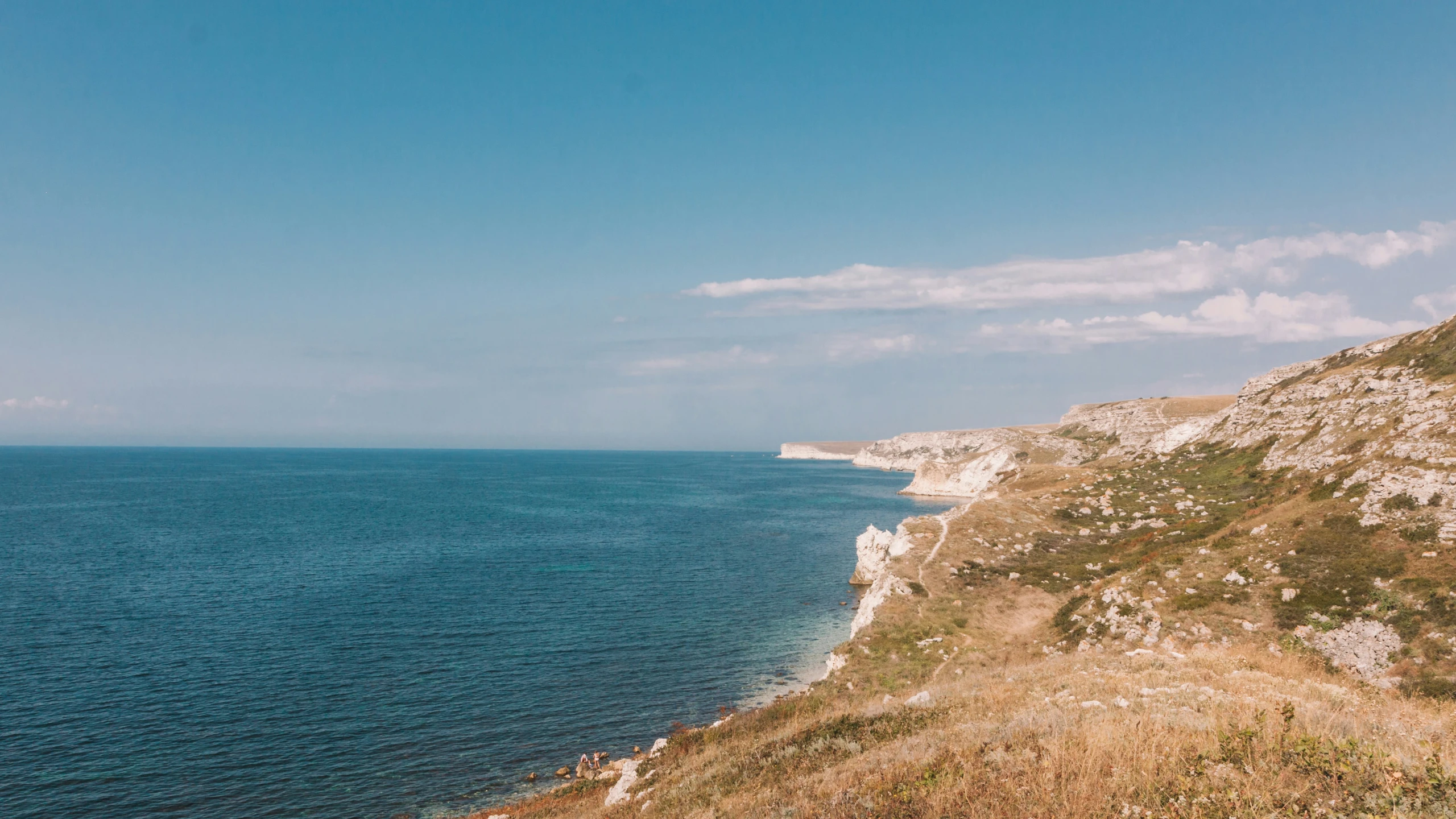 a road leading to the beach with cliffs on the shoreline