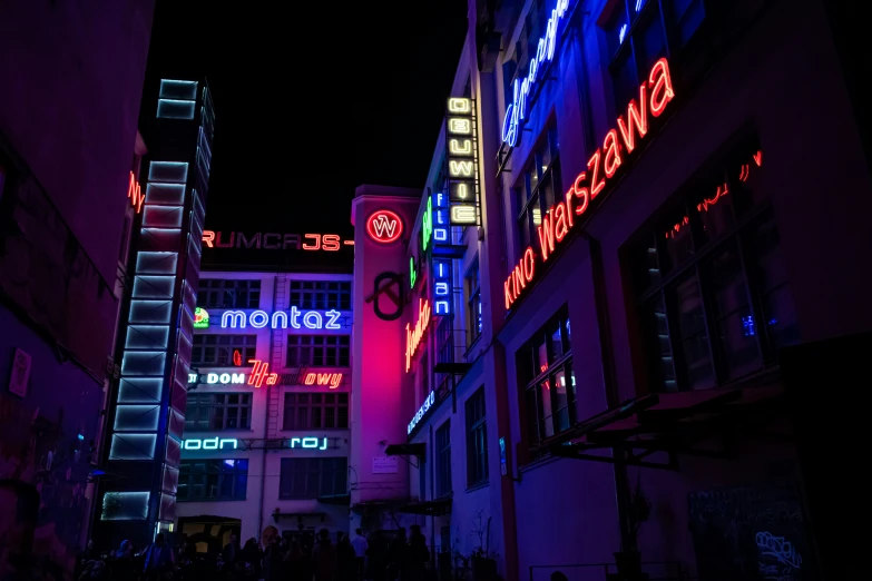 brightly lit building with people walking on sidewalk at night