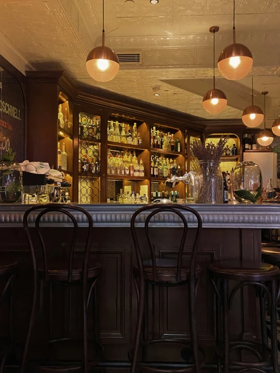 bar with three stools with lights above them