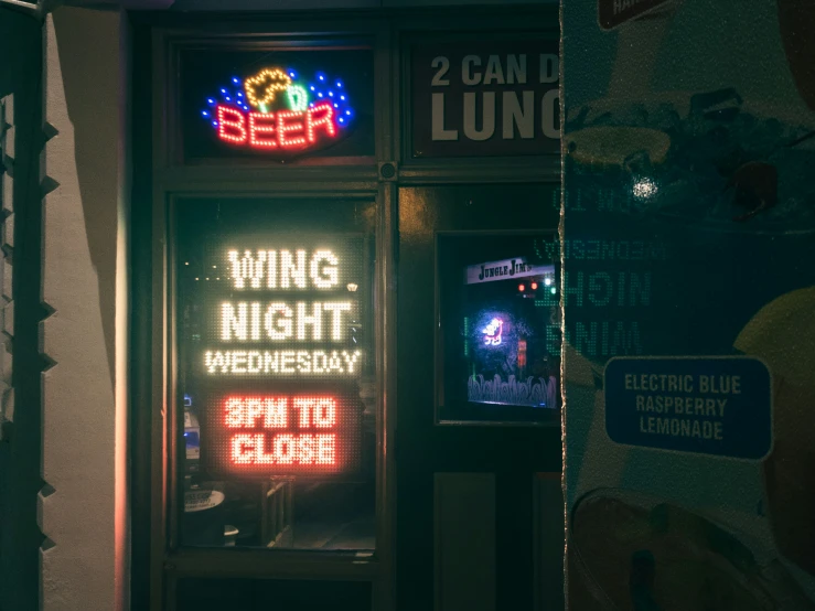 a neon sign on a street next to some advertising signs