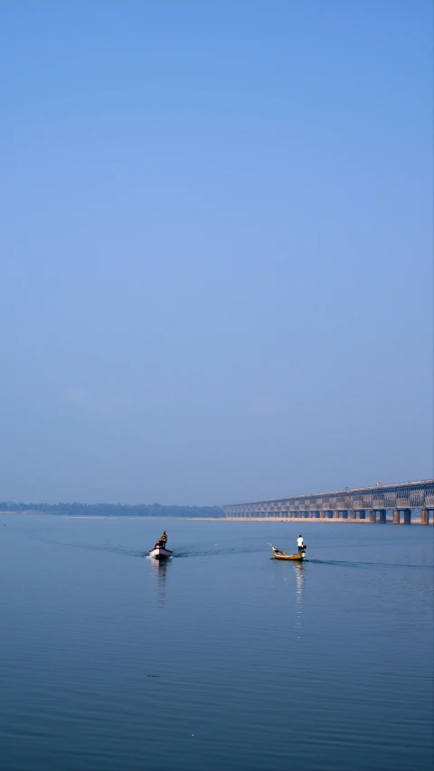 two people rowing a boat across water with an ocean in the background