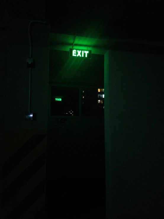 exit sign lit in the dark with a green light