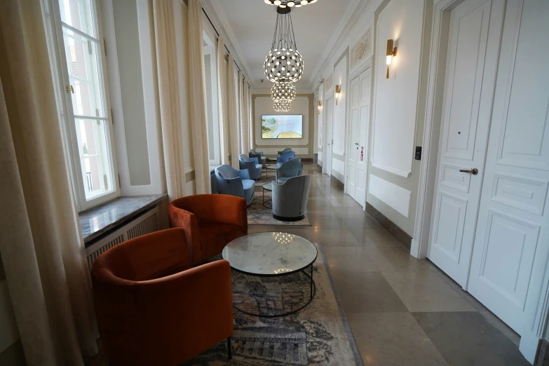 a long hallway with chairs and a chandelier