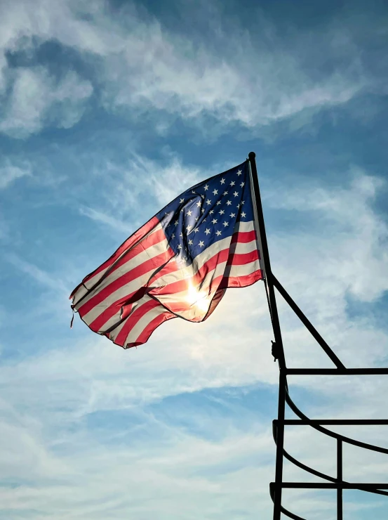 a flag waving on the wind in front of a cloudy sky