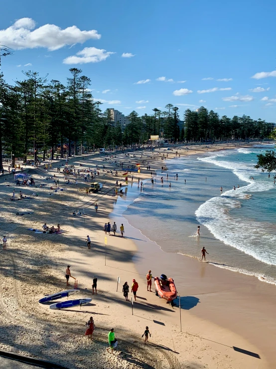 many people walk along the beach in front of the water