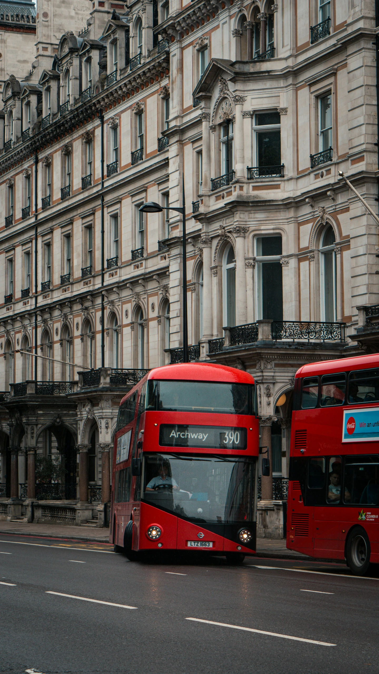 two red double decker buses parked next to each other in front of large buildings