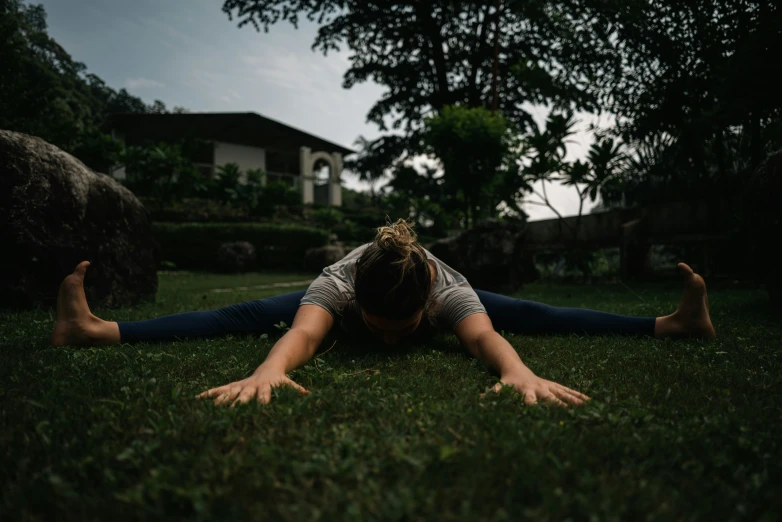 a woman laying on the grass doing a yoga pose