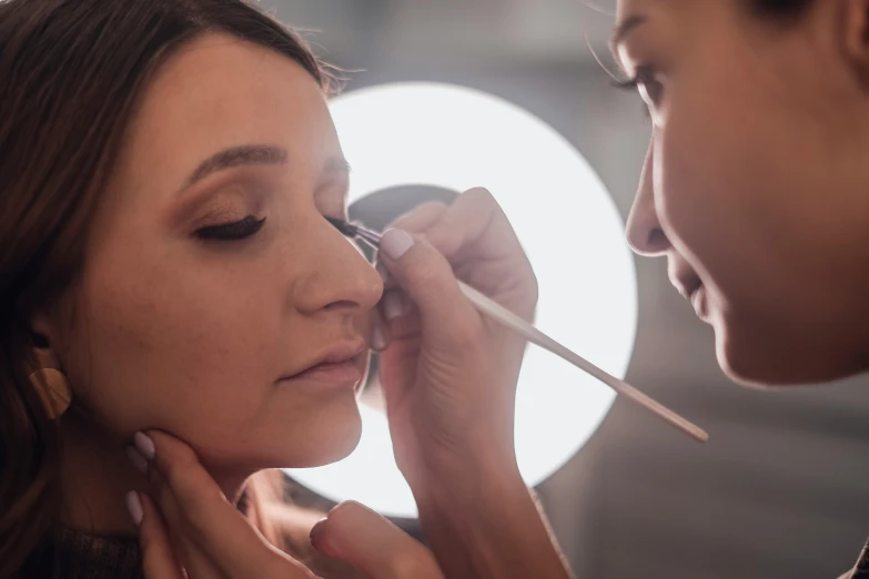 a woman with a nose brush on her lips getting makeup done