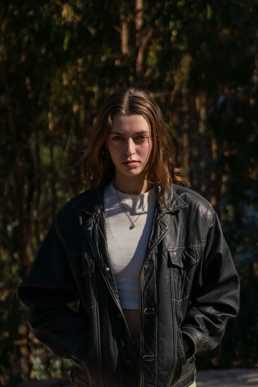 a young woman in a jacket standing near a road