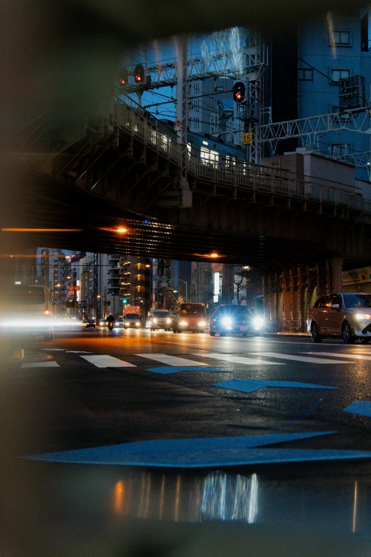 an elevated bridge over a busy intersection with cars coming in at night