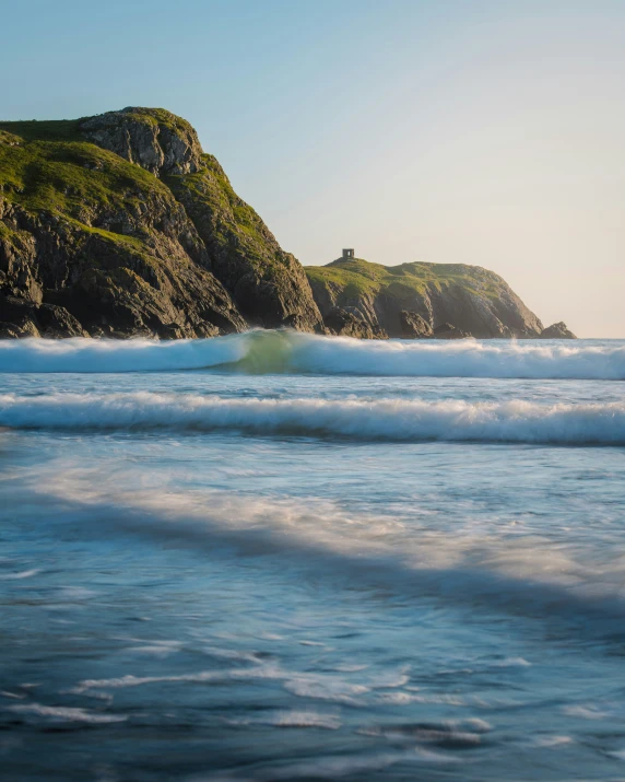 small wave coming toward a large beach with a rock