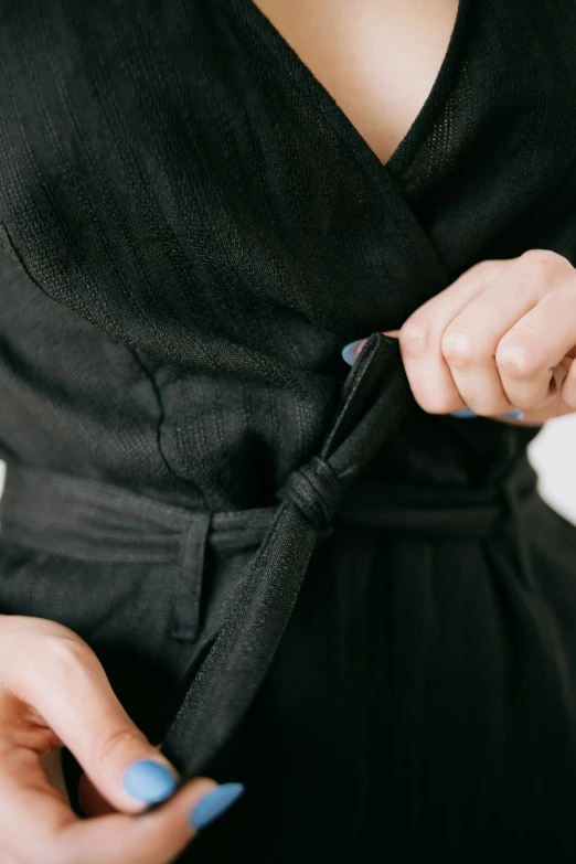 a woman in black dress tying a blue band around her tie