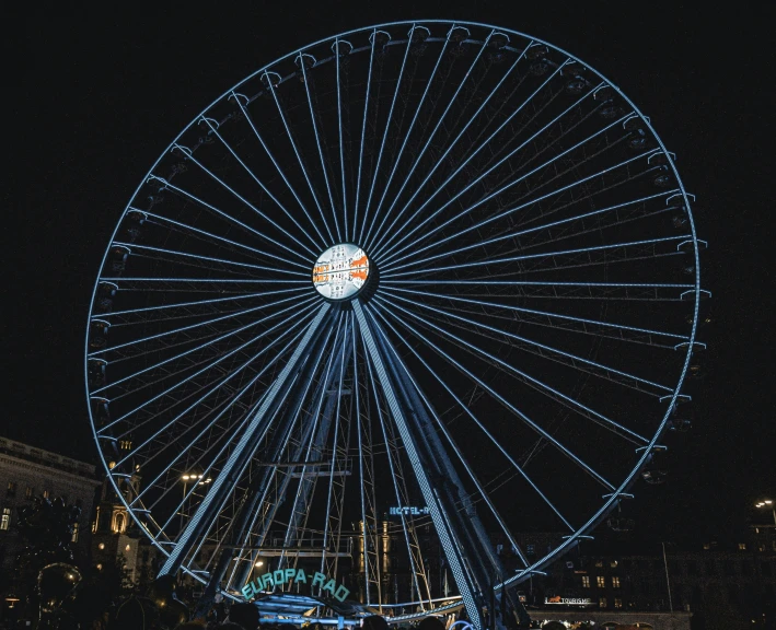 an illuminated ferris wheel in the city during the night