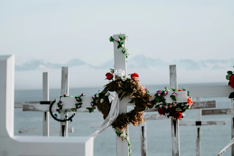 cross decorated with roses next to the ocean