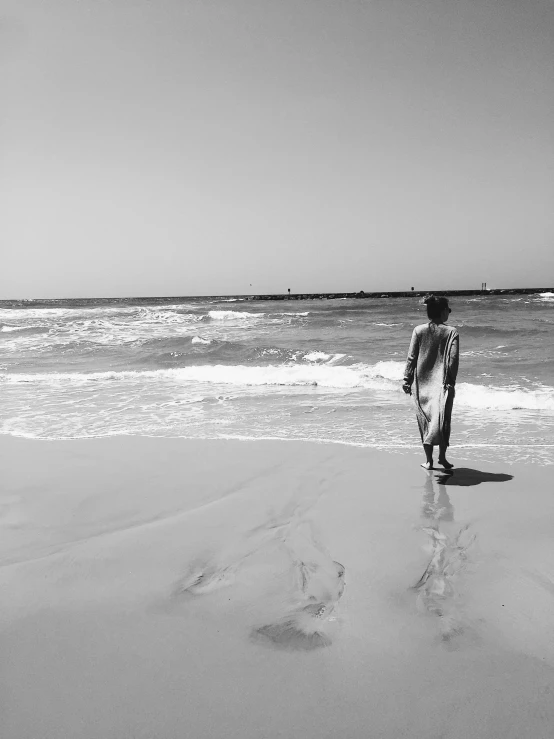 a man walks along the beach carrying a surf board