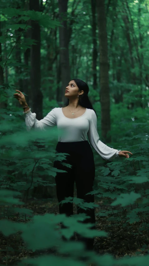 a woman is standing in the middle of the forest