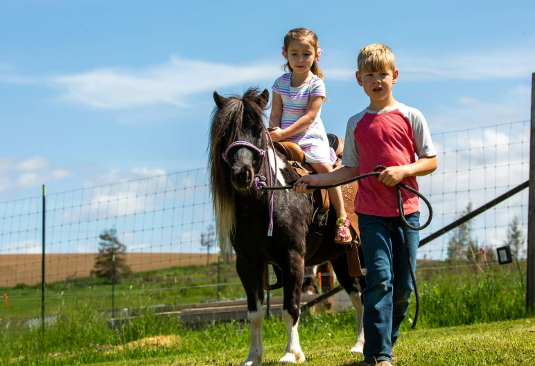 two little girls riding horses down a field