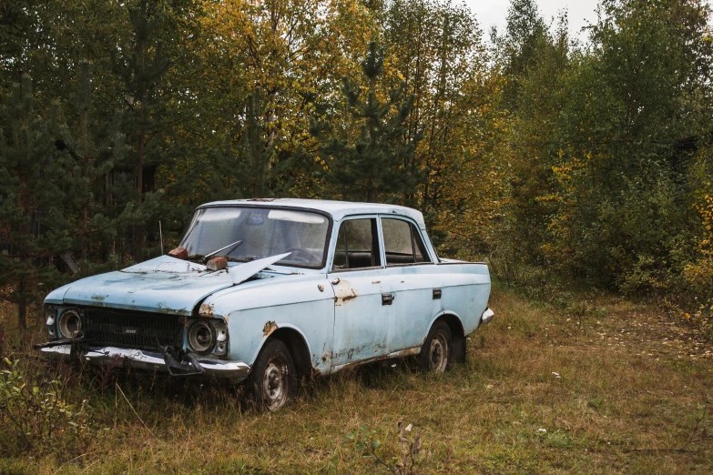 the abandoned blue pickup truck is sitting in a field