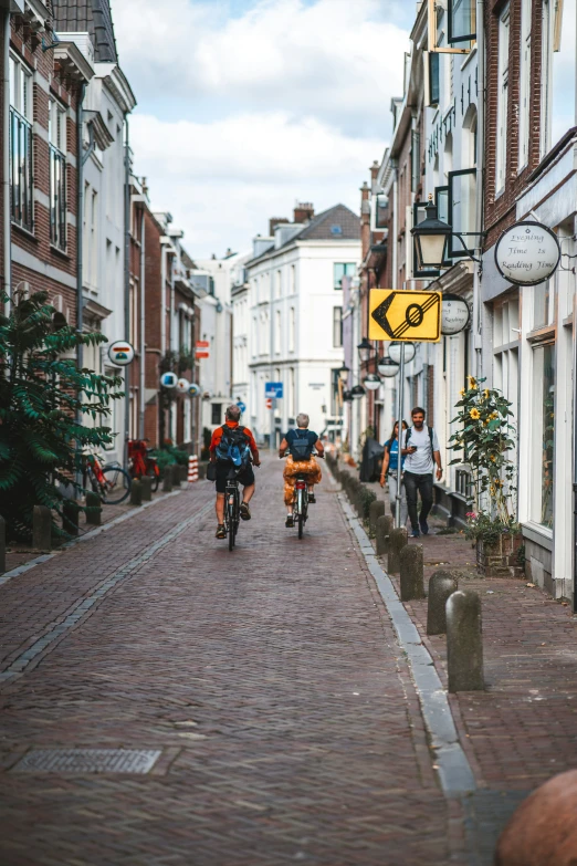 a small group of people riding bicycles down a cobblestone street