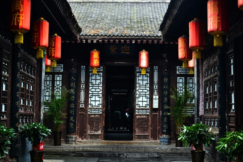 an oriental house with red lanterns above the doorway