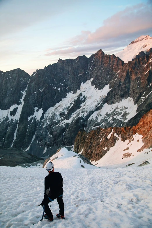 a man stands in the snow by some mountain peaks