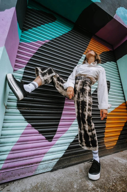 the woman is posing in front of a colorful mural