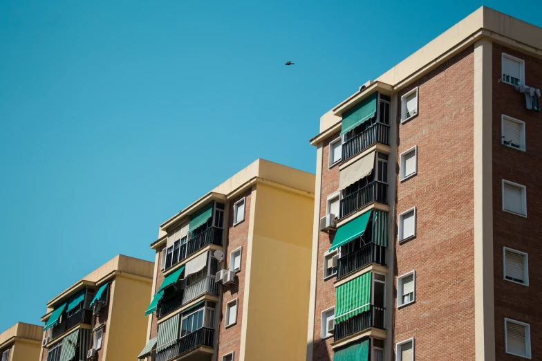 a bird flying through the blue sky next to brick building