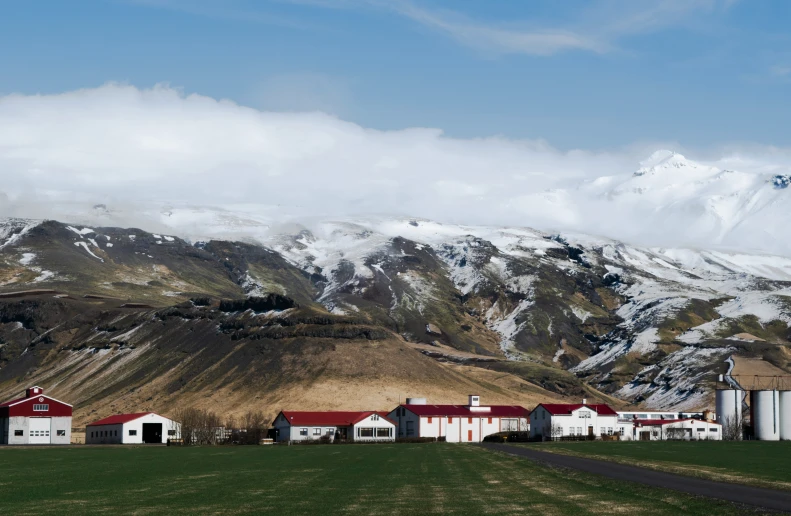 a white barn is on the side of a hill