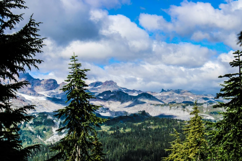 a view of mountains and trees against a cloudy sky