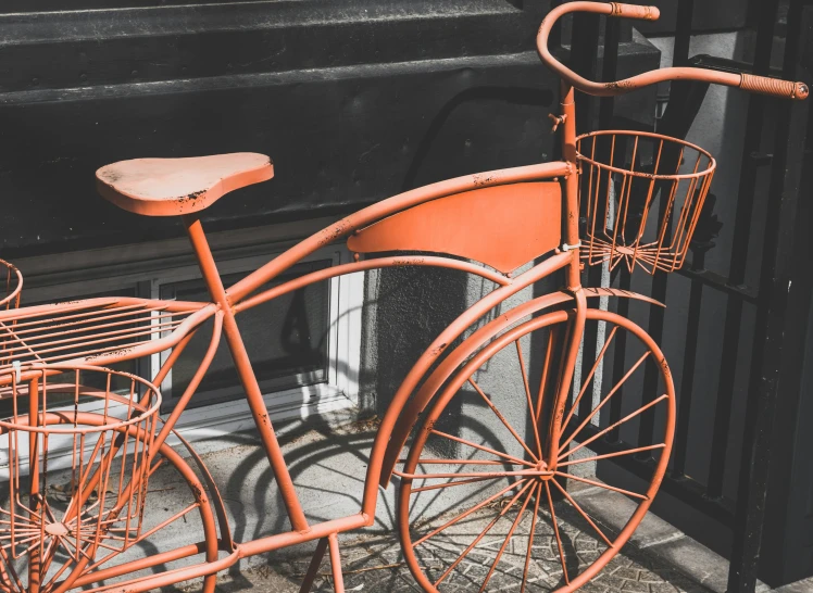 a red bike is parked next to a black building