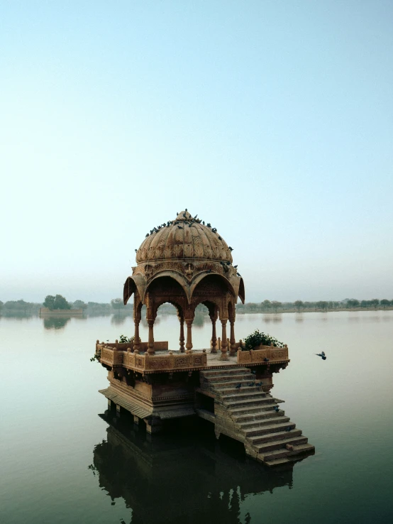a pavilion is near steps on the side of a large body of water