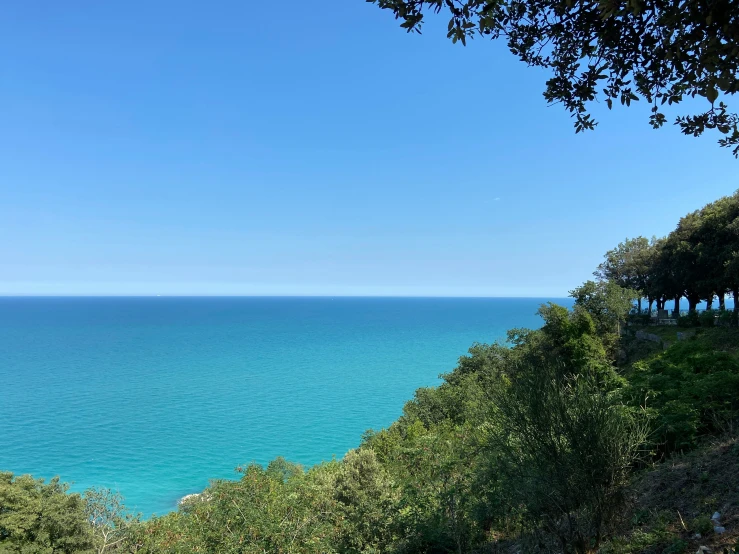 the ocean is blue and green with a bench in front