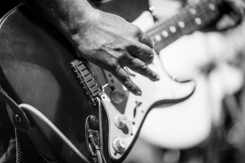 the hands of a man playing the electric guitar
