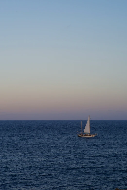 a sailboat with no sails in the middle of an ocean