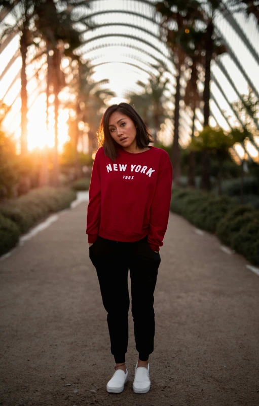 a woman stands on the sidewalk, with palm trees around her