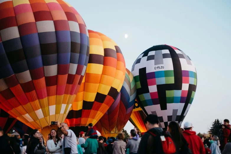 many people gathered around a group of  air balloons in the sky