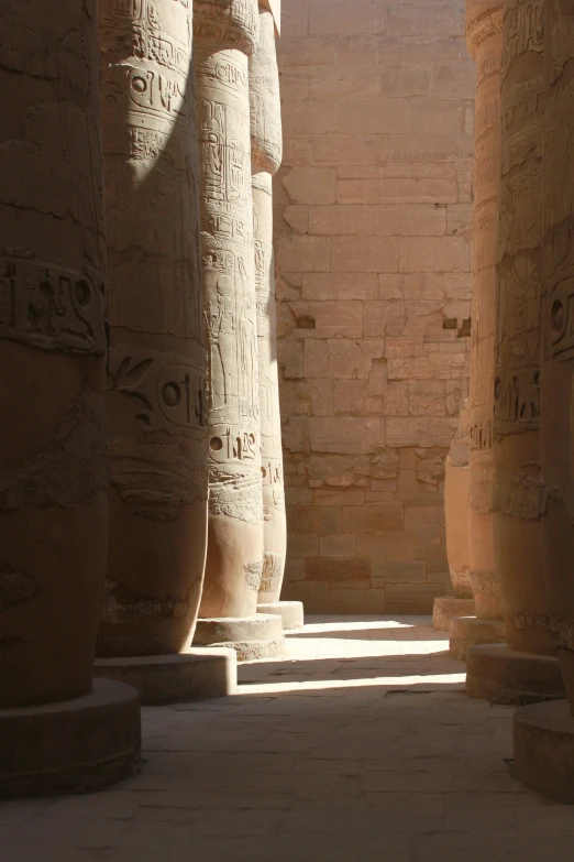 several tall stone columns stand in front of the sun