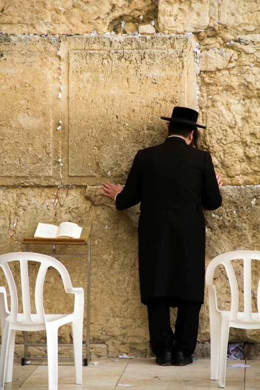 a man wearing a top hat leaning against a wall