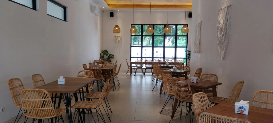 many tables and chairs in a restaurant with the door open